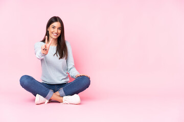 Young caucasian woman isolated on pink background smiling and showing victory sign