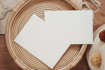 White invitation cards in a wooden wicker basket in boho style