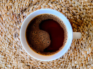 Top view of a cup of coffee, isolated on wicker. Shaped like a ying yang.