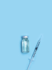 Syringe with medicine from glass vial on light blue background. Vaccination against influenza, covid 19, measles, coronavirus disease. Vaccination and immunization concept
