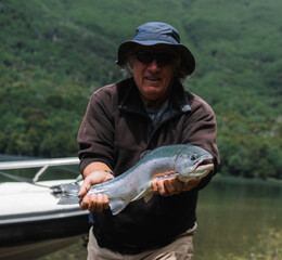 1 big man fisherman holding a rainbow fish smiling and looking at the camera