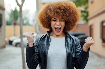 african woman happy and excited celebrating victory expressing big success, power, energy and positive emotions. Celebrates new job joyful, outdoor