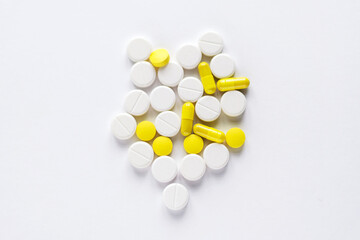 Pile of yellow and white tablets on white background.