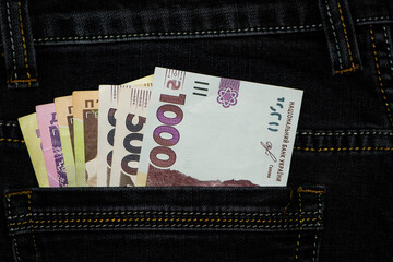 money in your pocket. Ukrainian hryvnia. 1000, 500, 200 bills in a pants pocket. jeans trousers, a lot of money of different denominations in my pocket. business, trade or financial transactions.