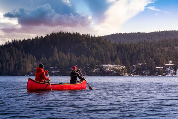 Couple friends on a wooden canoe are paddling in water. Sunset Sky Art Render. Taken in Indian Arm, near Deep Cove, North Vancouver, British Columbia, Canada. Concept: Adventure, Sport, Explore