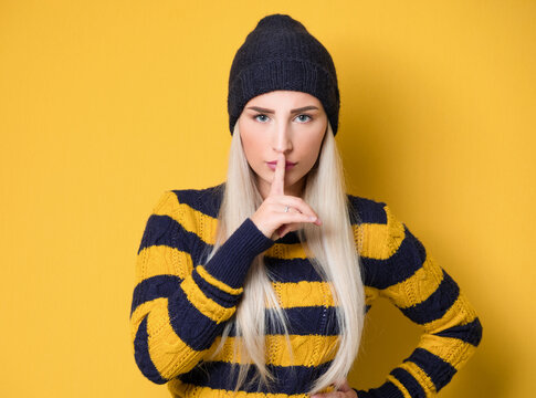 Psst. Young woman holding finger on lips, keep the secret concept, isolated on white background