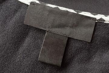 Blank black laundry care clothes label on black fabric texture background