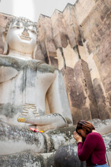 Fototapeta na wymiar Asian woman to pay respect to Buddha statue at Wat Si Chum ,an ancient religious site of sukhothai , Thailand