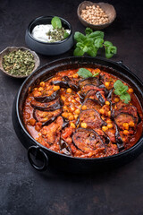 Modern style slow cooked Lebanese vegetarian eggplant stew maghmour served with chickpeas as close-up in a design pot