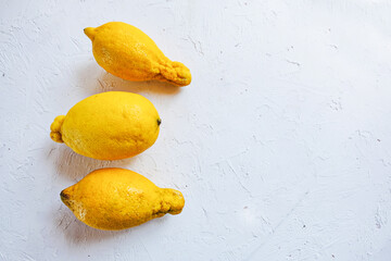 Trendy ugly organic fruits - three yellow lemons on the table with copy space for text. Horizontal...