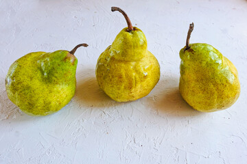 Trendy ugly organic fruits - three yellow pears on the table with copy space for text. Vertical...