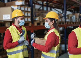 Industrial delivery worker inside warehouse wearing protective face masks for coronavirus outbreak