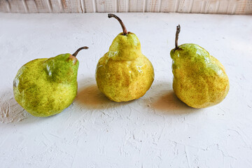 Trendy ugly organic fruits - three yellow pears on the table with copy space for text. Vertical...