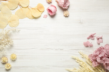 Flat lay composition with beautiful fresh and dry flowers on white wooden background. Space for text