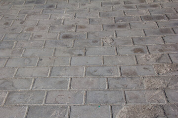 The sidewalk is paved with square decorative tiles.