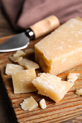 Parmesan cheese with knife on wooden board, closeup