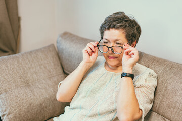 Attractive senior lady wearing reading glasses on the sofa