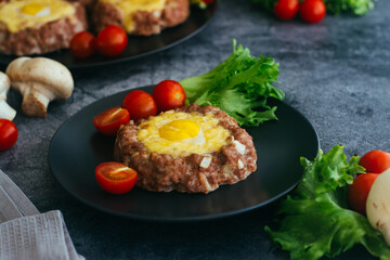 Beefsteak with egg on a plate. Delicious hot dish. The dish is decorated with cherry tomatoes and herbs. Beefsteak on a plate 