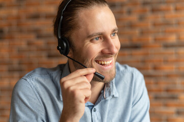 Cheerful male support officer wearing headset takes a call, friendly call center operator talking...