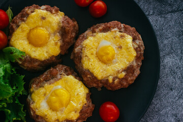 Beefsteak with egg on a plate. Delicious hot dish. The dish is decorated with cherry tomatoes and herbs. Beefsteak on a plate 