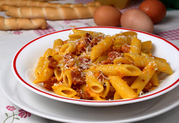 Penne rigate alla carbonara. Piatto con pasta italiana su tavolo apparecchiato per il pranzo.