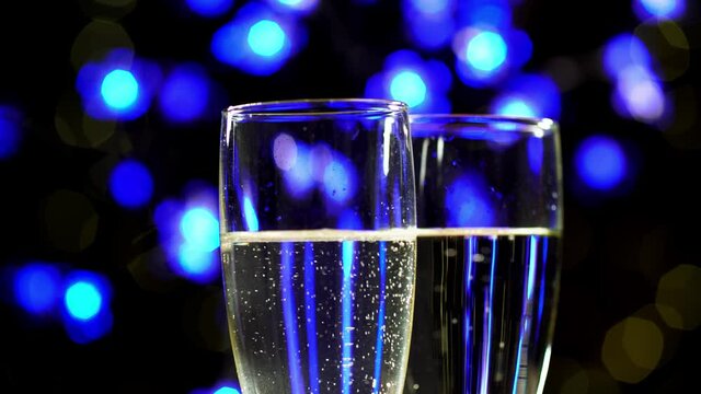 Two wine glass full of sparkling wine on blue bokeh background. Closeup view bubbles in two transparent bocals with champagne. Theme of celebrating valentine day holiday or spending romantic evening