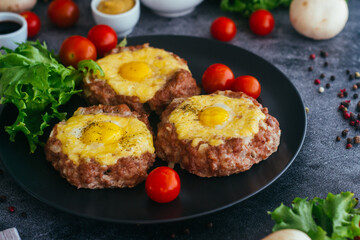 Beefsteak with egg on a plate. Delicious hot dish. The dish is decorated with cherry tomatoes and herbs. Beefsteak on a plate 