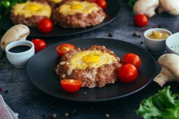 Beefsteak with egg on a plate. Delicious hot dish. The dish is decorated with cherry tomatoes and herbs. Beefsteak on a plate 