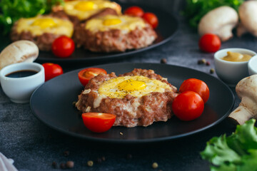 Beefsteak with egg on a plate. Delicious hot dish. The dish is decorated with cherry tomatoes and herbs. Beefsteak on a plate 