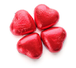 Heart shaped chocolate candies in red foil on white background, top view