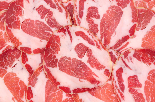 Capocollo or coppa traditional Italian dry cured pork meat slices background