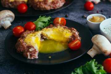 Beefsteak with egg on a plate. Delicious hot dish. The dish is decorated with cherry tomatoes and herbs. Beefsteak on a plate 