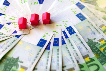 100 euro bills and miniature houses, concept of the cost of buying a home.