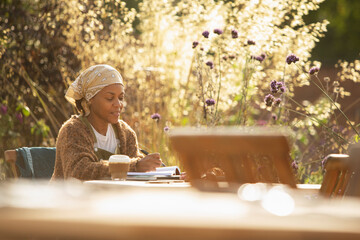 Woman working at cafe table in sunny garden
