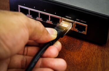 Person plugging in cable to wireless router. Close up.	
