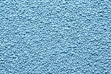 Blue granular mineral fertilizer as background, top view