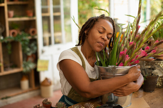 Serene woman hugging bucket of flowers in florist shop