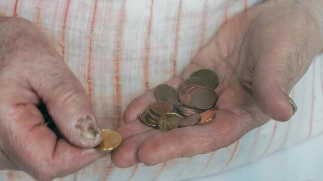 old woman counts pennies in her hands. pensioner counts coins. old woman's hands close-up