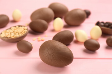Sweet chocolate eggs on pink wooden table