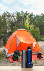 Modern thermo bottles outdoors. Camping season