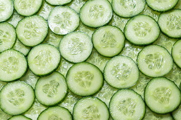 Fresh green slices of cucumber as background.