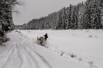 Snowmobile racing on the Volga-Uvod channel on a cloudy winter day.