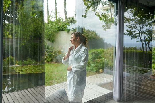 Woman in bathrobe looking out window
