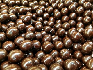 Close-up black round chocolate. Background small chocolates and detail shots.