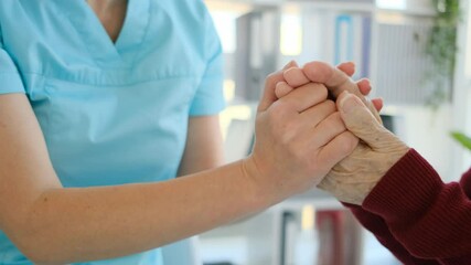 Close up view of caregiver holding hands of elderly woman in nursing home