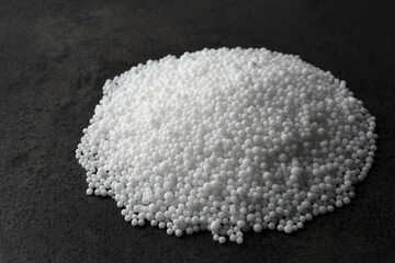 Pellets of ammonium nitrate on grey table. Mineral fertilizer