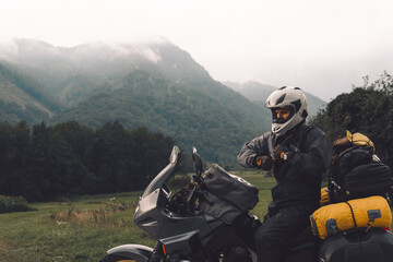 A motorcycle driver with motorbike, Adventure vacation, biker dressed in raincoat. sealed bag,...