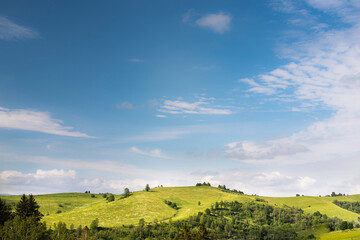 Green hilly landscape and blue sky during summer.