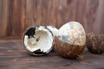 Rotten coconut on a wooden background. Spoiled products.