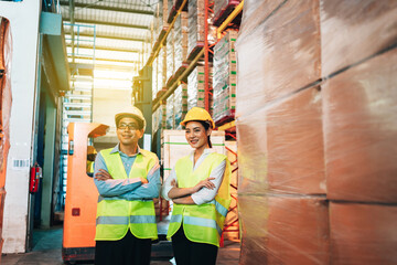 Obraz premium Working Team at warehouse. Manager man and asian woman warehouse worker standing with crossed arms to look at the camera.background driver at Warehouse forklift loader works with goods